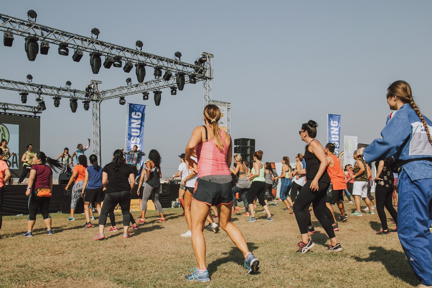Participants follow instructors during an outdoor group fitness class.