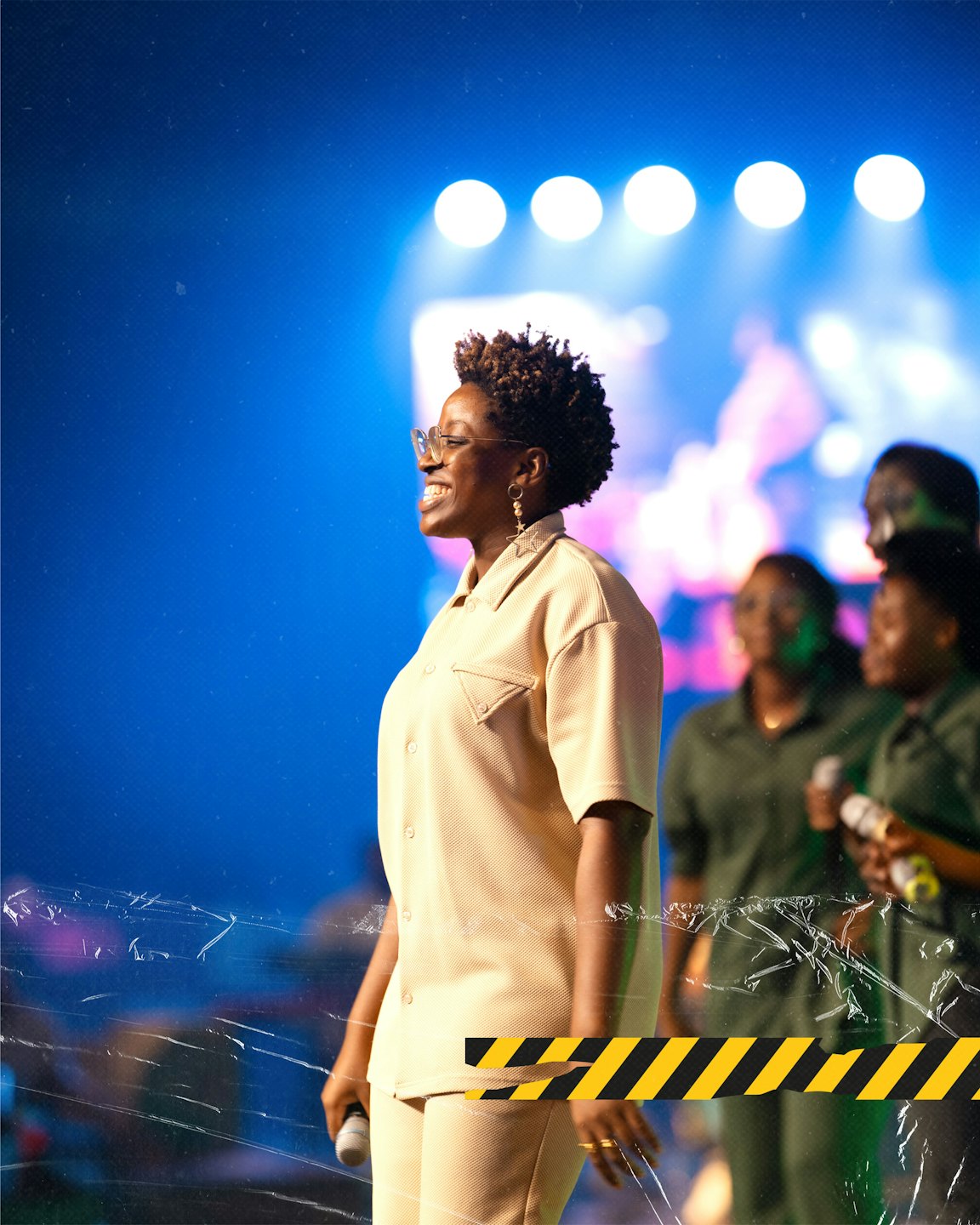 Young Black woman sings joyfully into a microphone on stage.