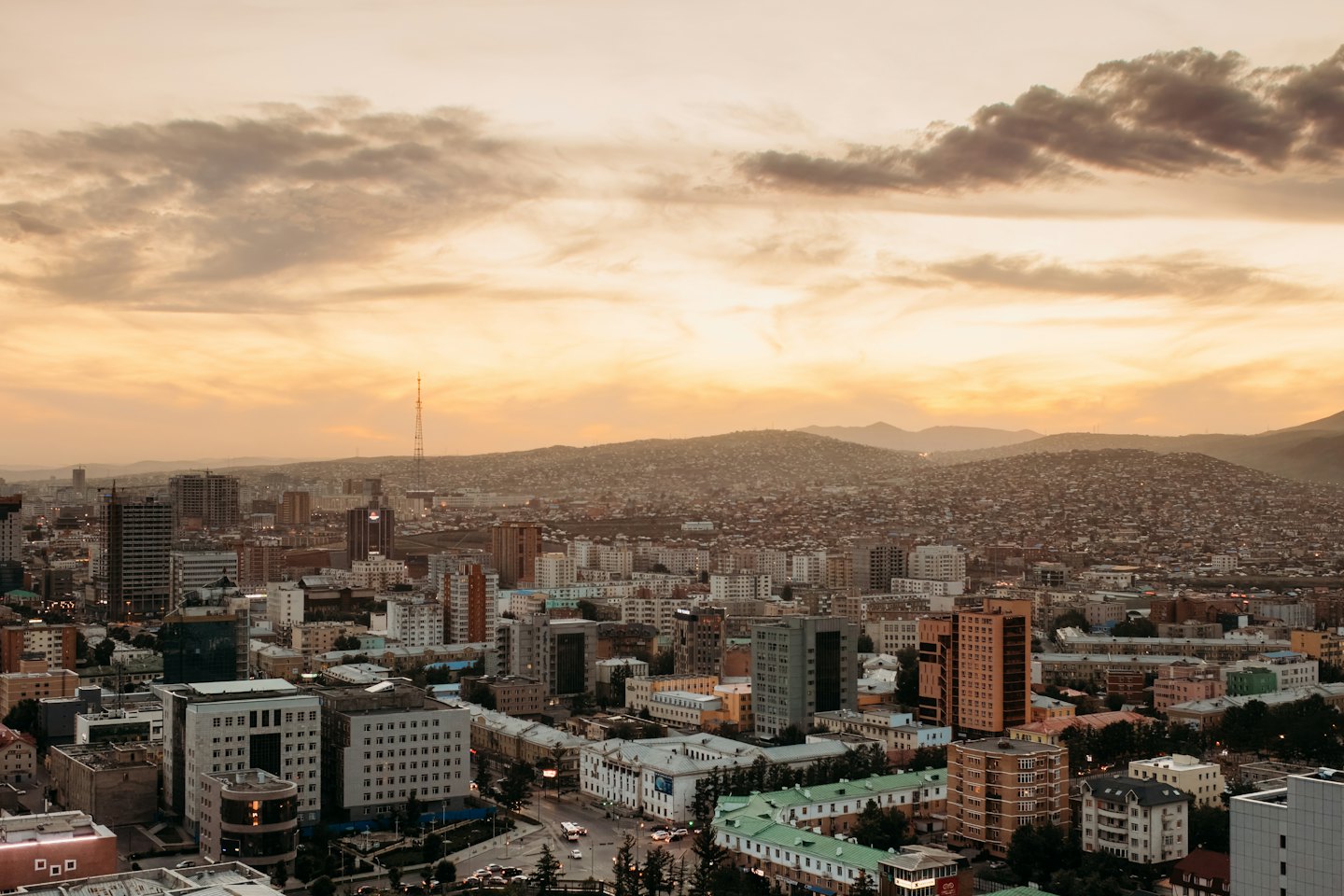 City skyline at sunset with distant hills.